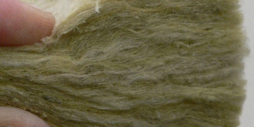 Hand holding a sample of greenish fibrous insulation material