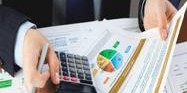 Person calculating finances with a calculator and charts