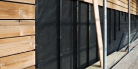 Exterior of a building being renovated with black weatherproofing or insulation