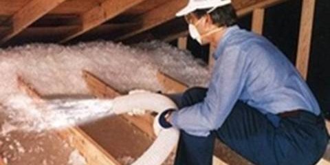 Worker spraying loose-fill insulation into an attic space